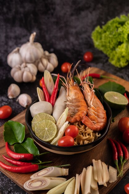 Tom Yum Kung in a bowl with tomato, chili, lemongrass, garlic, lemon, and kaffir lime leaves