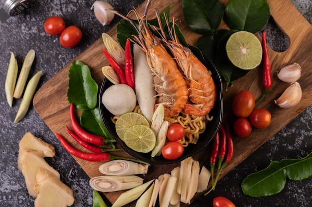 Tom Yum Kung in a bowl with tomato, chili, lemongrass, garlic, lemon, and kaffir lime leaves