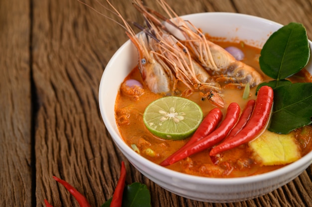 Tom Yum Kung Thai hot spicy soup shrimp with lemon grass,lemon,galangal and chilli on wooden table, Thailand Food