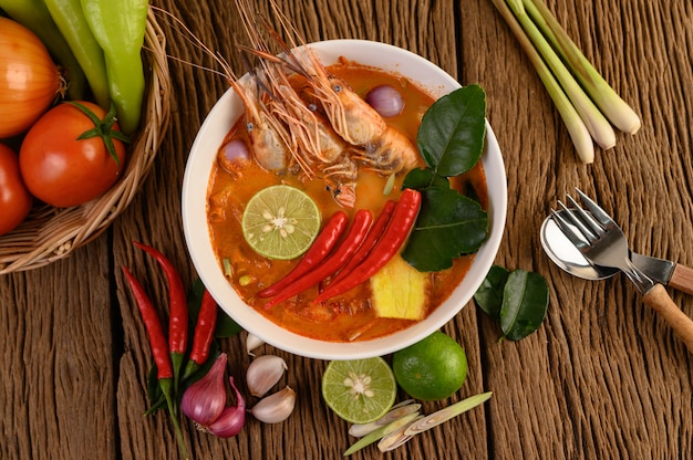 Tom Yum Kung Thai hot spicy soup shrimp with lemon grass,lemon,galangal and chilli on wooden table, Thailand Food