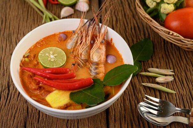 Tom Yum Kung Thai hot spicy soup shrimp with lemon grass,lemon,galangal and chilli on wooden table, Thailand Food