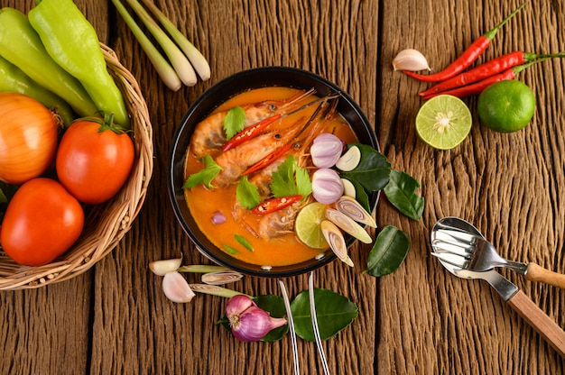 Tom Yum Kung Thai hot spicy soup shrimp with lemon grass,lemon,galangal and chilli on wooden table, Thailand Food