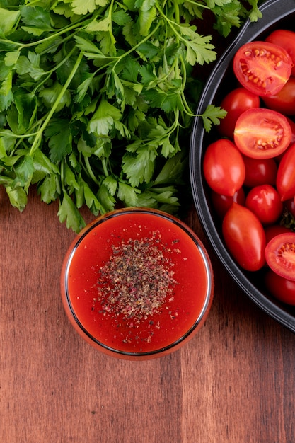 Free photo tomato juice in glass and cherry tomatoes in pan top view