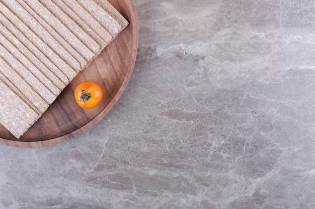 Free Photo tomato a stack of crispbreads on the wooden board , on the marble background.