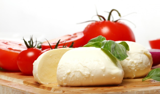 Tomatoes, basil and mozzarella on wooden board