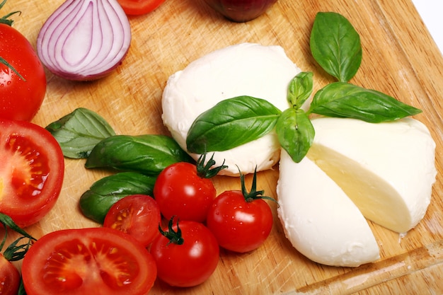 Tomatoes, basil and mozzarella on wooden board