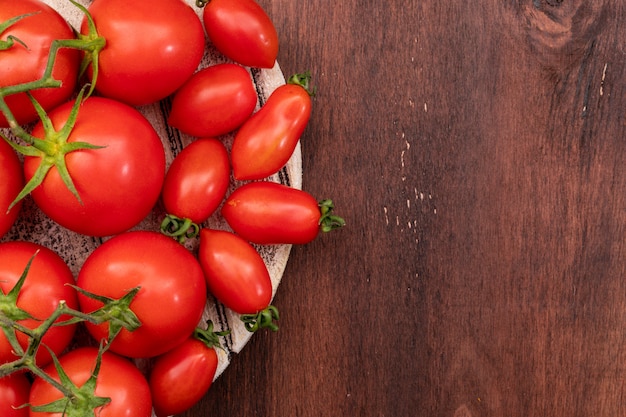 tomatoes and cherry tomatoes on wooden texture board