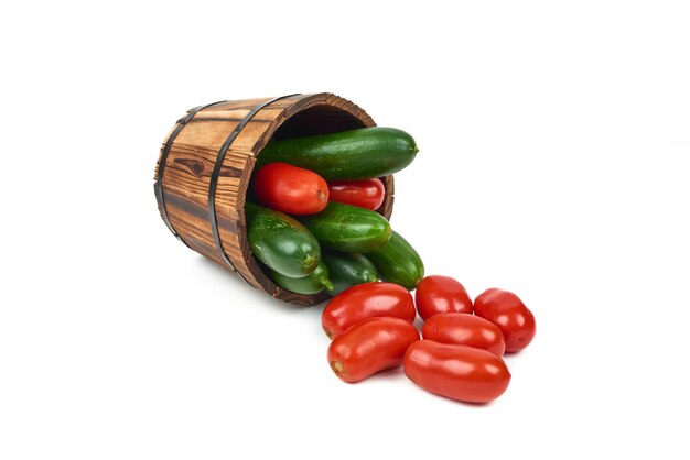 Tomatoes and cucumbers out of a wooden bucket on the white.