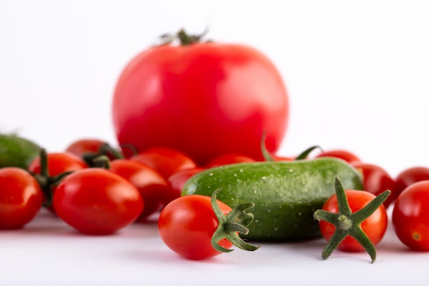 Tomatoes and cucumbers on white background