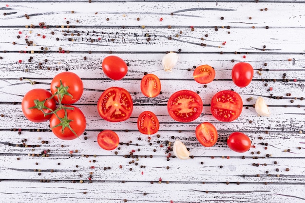 tomatoes garlic and black pepper top view on white wooden texture