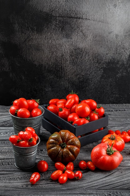 Free photo tomatoes in mini buckets, wooden box on grey wooden and grunge wall. high angle view.