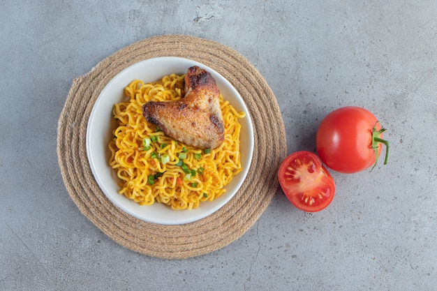 Tomatoes and noodle bowl on a trivet, on the marble background. 