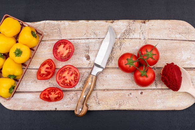 Tomatoes top view concept on cutting board with knife and pepper