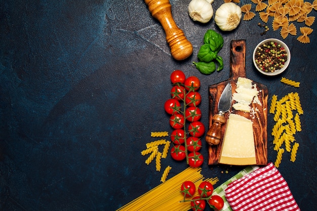 Tomatoes with a cutting board with cheese, pasta and spices