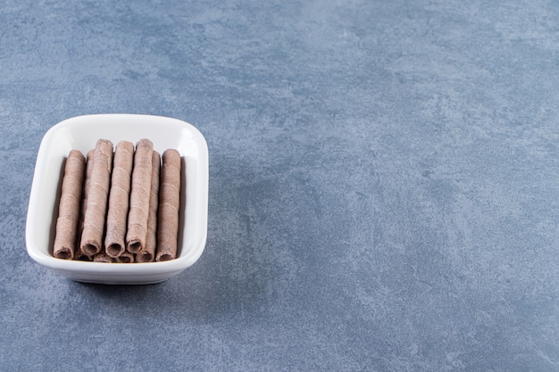 Toothsome chocolate wafer roll in a bowl on the marble surface