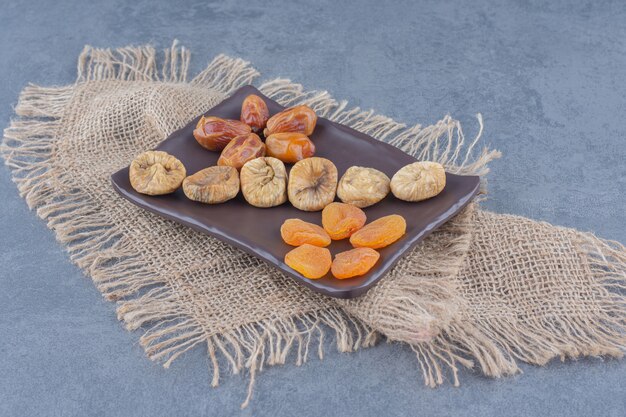 Toothsome dried fruits on the board, on the trivet, on the marble background. 