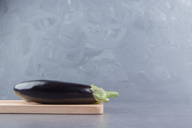 Toothsome eggplant on the board, on the marble surface