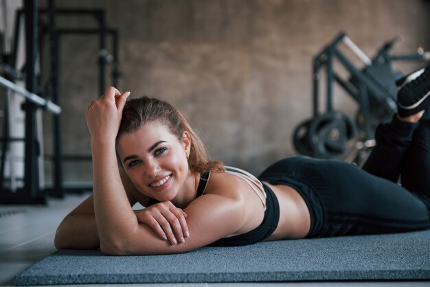 Toothy smile. Photo of gorgeous blonde woman in the gym at her weekend time