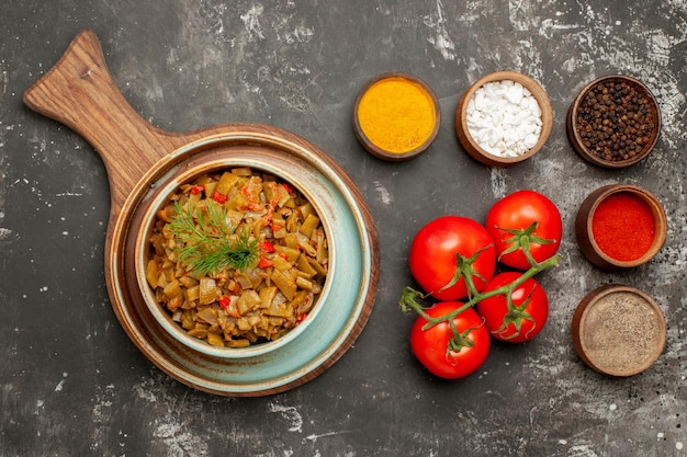 Free Photo top close-up view appetizing dish appetizing dish next to the bowls of colorful spices on the dark table