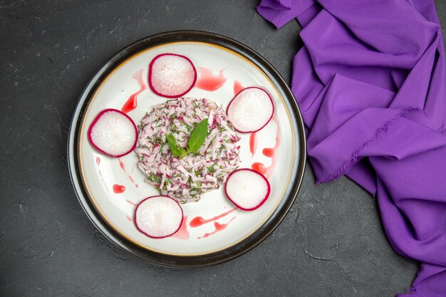 Top close-up view an appetizing dish plate of radish herbs and sauce purple tablecloth