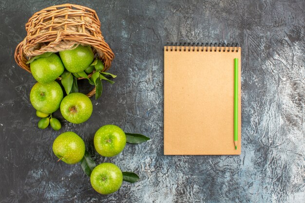 Top close-up view apples basket of apples with leaves notebook pencil