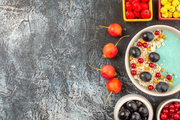 Top close-up view berries cherry colorful berries oatmeal in the bowls on the dark table