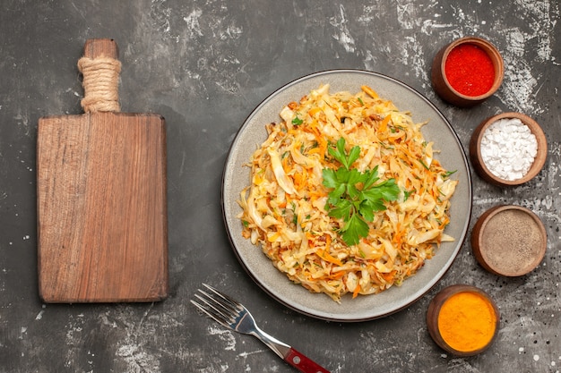 Top close-up view cabbage plate of cabbage carrots fork colorful spices wooden board