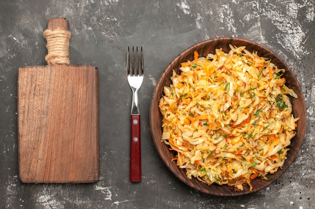 Top close-up view cabbage with carrots the appetizing carrots herbs cabbage board fork