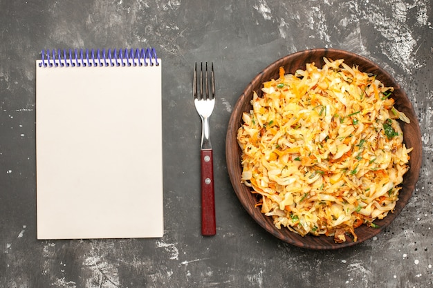 Top close-up view cabbage with carrots the appetizing carrots herbs cabbage notebook fork