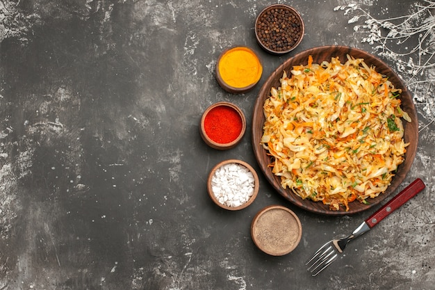 Top close-up view cabbage with carrots plate of cabbage carrots herbs fork bowls of spices