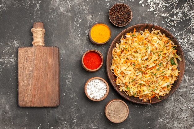 Top close-up view cabbage with carrots plate of cabbage the cutting board bowls of spices