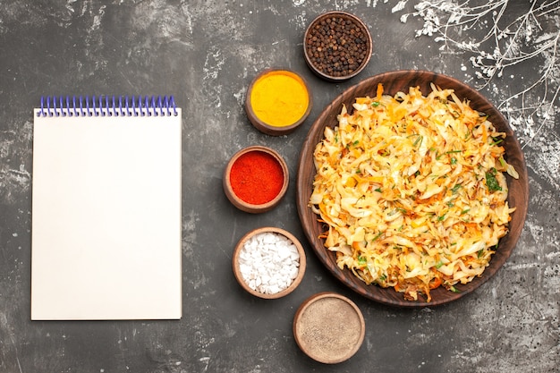 Free Photo top close-up view cabbage with carrots plate of cabbage white notebook bowls of spices