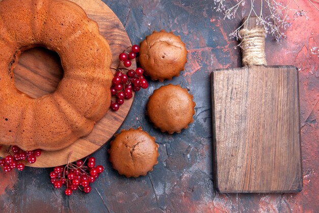 Top close-up view cake an appetizing cake with red currants cupcakes next to the cutting board