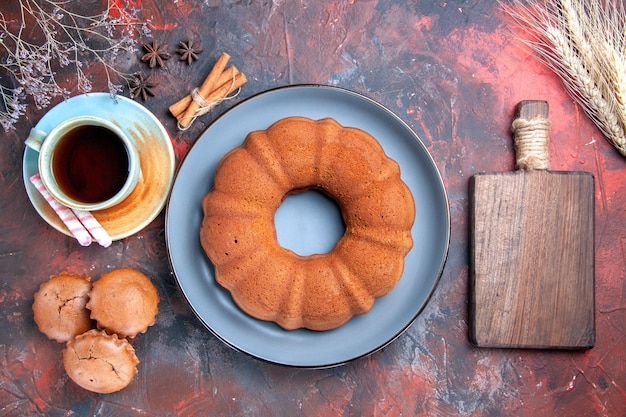 Top close-up view a cake a cup of tea sweets a cake cupcakes cinnamon and the cutting board