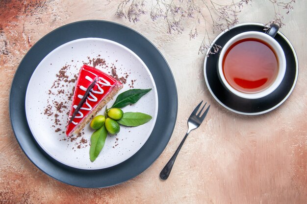 Top close-up view a cake plate of cake with chocolate sauces citrus fruits fork a cup of tea