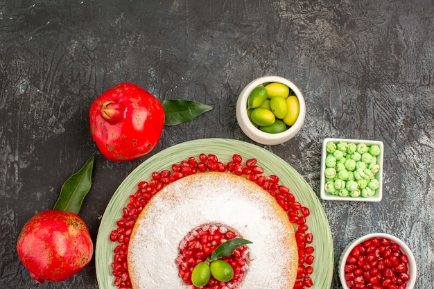 Top close-up view cake sweets pomegranates an appetizing cake citrus fruits green candies