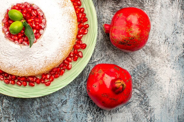 Top close-up view cake with pomegranates cake with seeds of pomegranate and two pomegranates