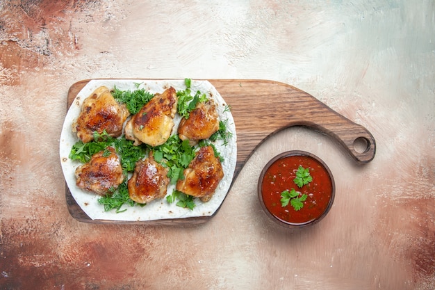 Free Photo top close-up view chicken bowl of sauce chicken with herbs on lavash on the cutting board