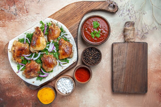 Top close-up view chicken chicken with onion herbs on lavash sauce colorful spices the board