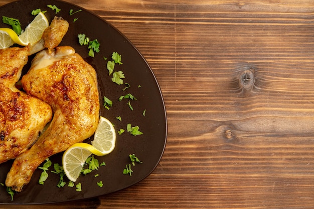 Top close-up view chicken with lemon chicken legs with herbs and lemon on the left side of the table