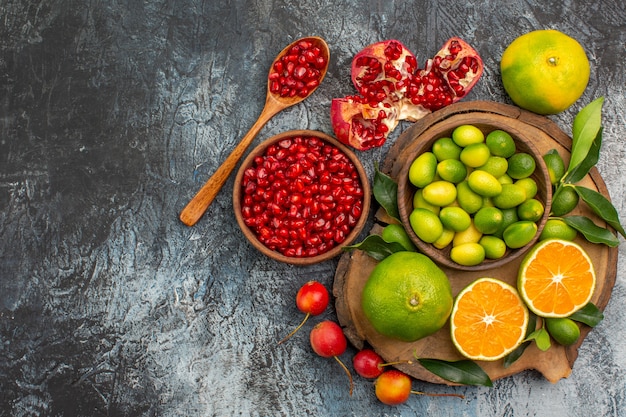 Top close-up view citrus fruits bowl of pomegranate seeds spoon citrus fruits on the board