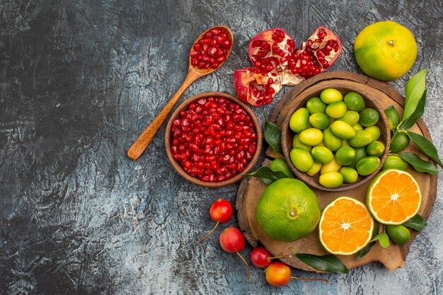 Top close-up view citrus fruits bowl of pomegranate seeds spoon citrus fruits on the board