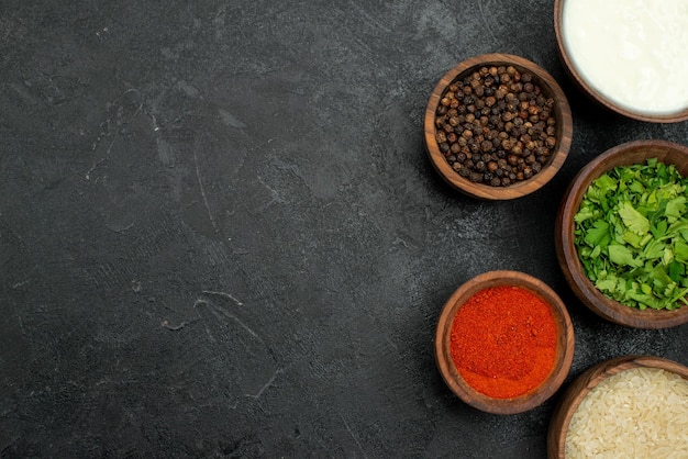 Top close-up view colorful spices bowls of colorful spices black pepper herbs sour cream and rice on the right side of table