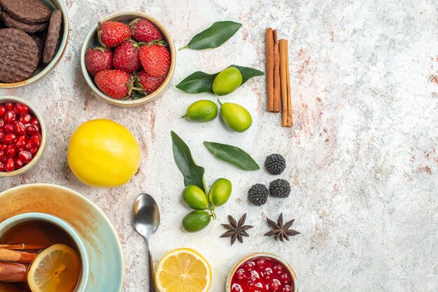 Top close-up view cookies and berries cinnamon the appetizing cookies strawberries lemon spoon a cup of tea citrus fruits on the table