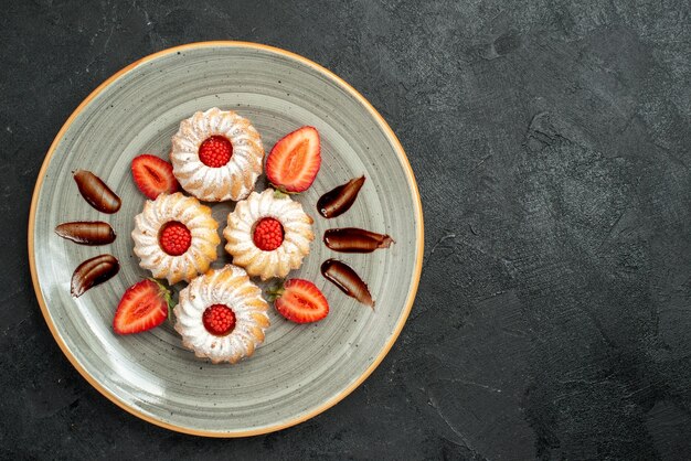 Top close-up view cookies with strawberry cookies with chocolate and strawberry on white plate on the left side of the table