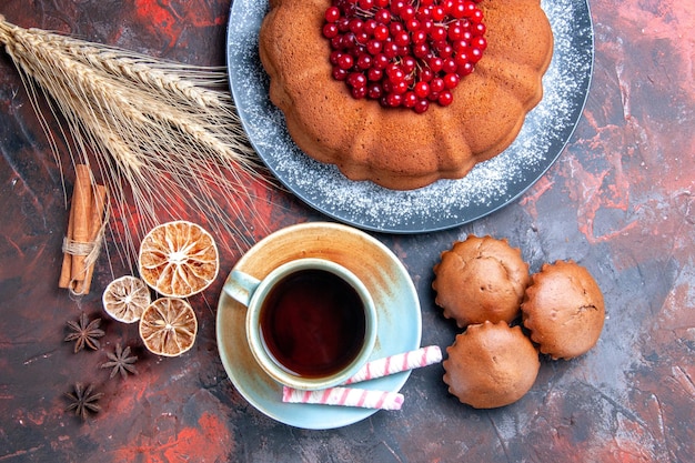 Top close-up view a cup of tea a cake with red currants sweets cupcakes a cup of tea cinnamon