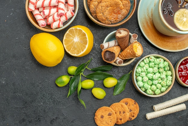 Top close-up view a cup of tea lemon citrus fruits a cup of herbal tea sweets cookies jam