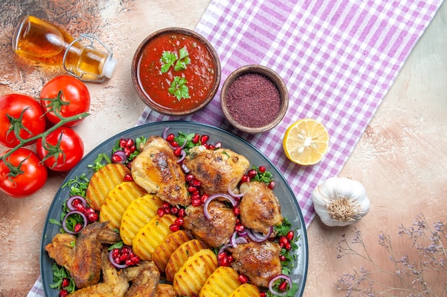 Top close-up view dish chicken wings potatoes oil tomatoes with pedicels spices on the tablecloth