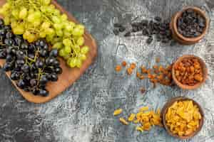 Free photo top close-up view dried fruits the appetizing grapes on the board dried fruits in the brown bowls