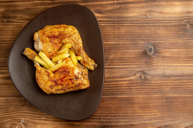 Free Photo top close-up view fast food plate of french fries and chicken legs on the left side of the wooden table